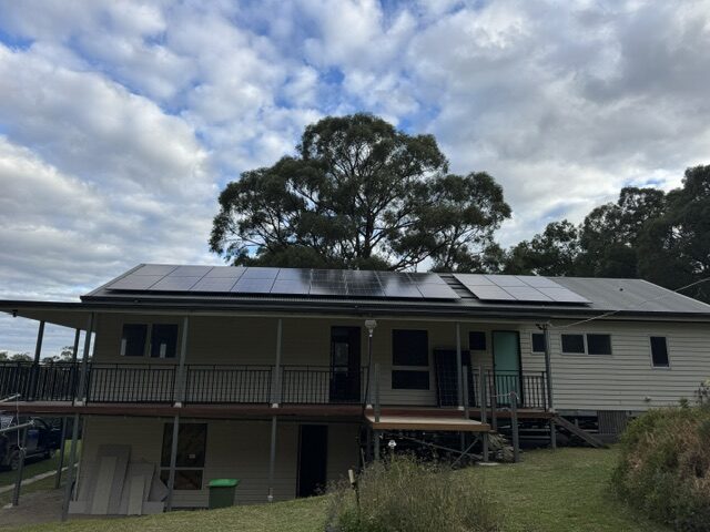 Rooftop solar array on a weatherboard home under a gum tree