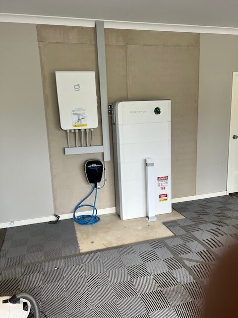 A tall SigenStor battery stack with EV charger beside it